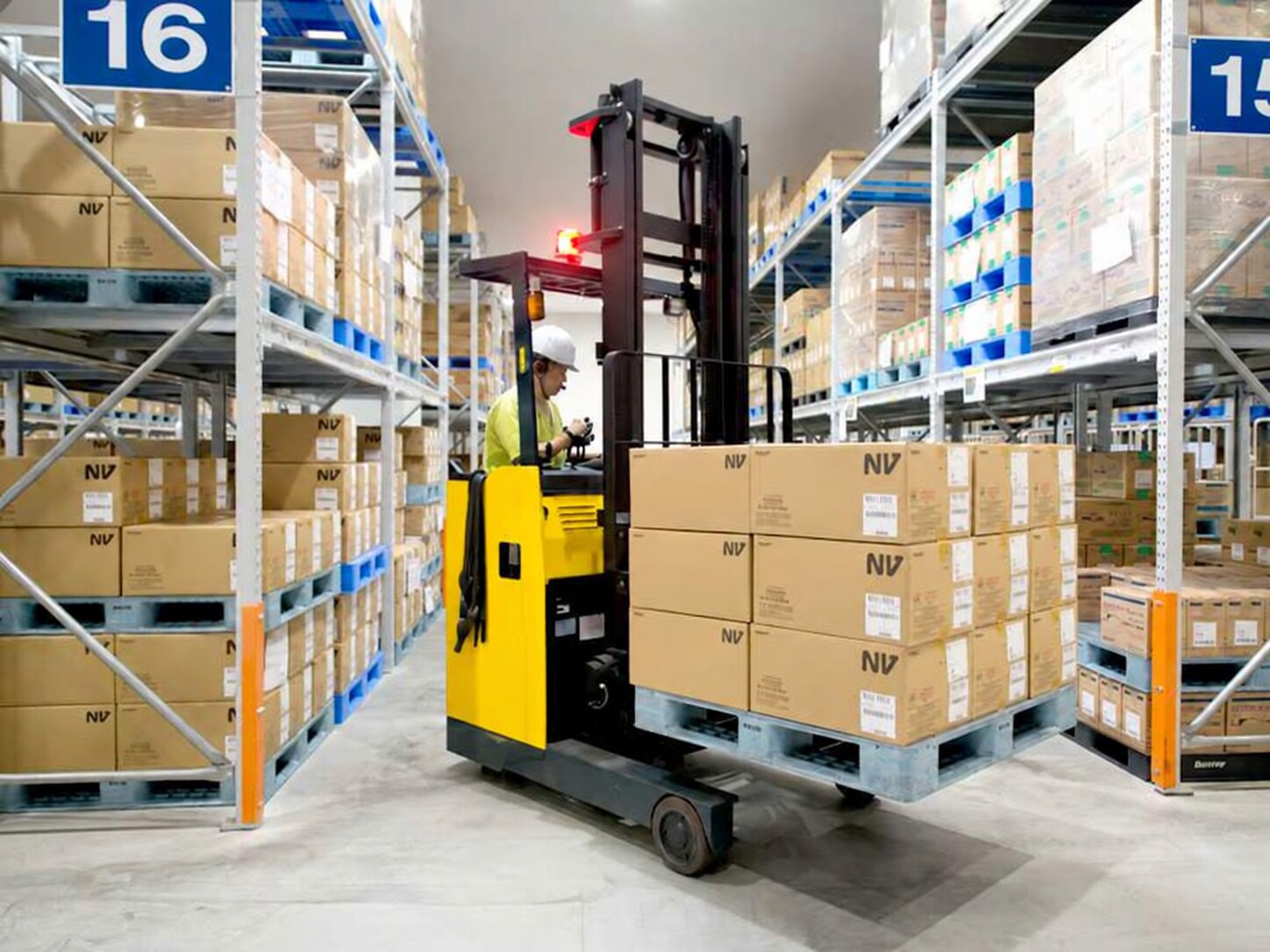 Reach truck handling a pallet between warehouse racks